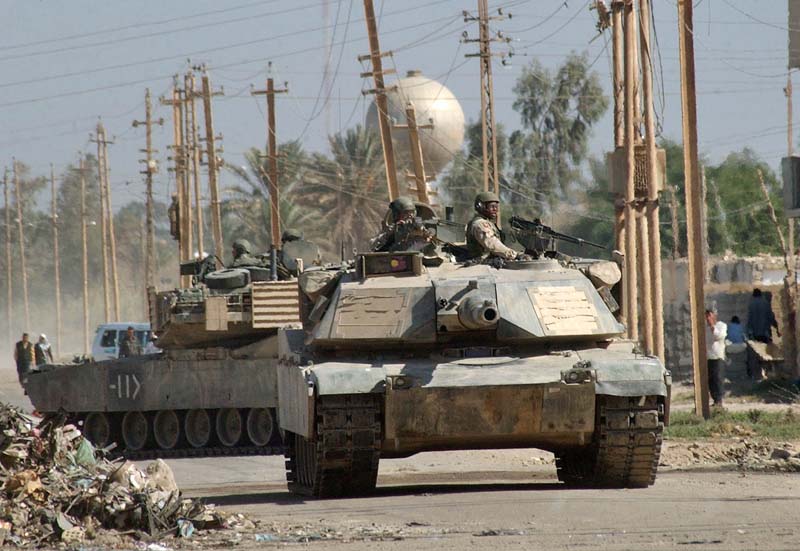 U.S. Army soldiers patrol with M1 Abrams tanks Baghdad's western end of Abu Ghraib, after U.S. troops clashed with Iraqi's for the second time in three days, Sunday, Nov 2, 2003. Local Iraqis said U.S. troops arrived earlier Sunday and ordered people to disperse from the marketplace and remove what the Iraqis said were religious stickers from walls. (AP Photo/Khaled Mohammed))